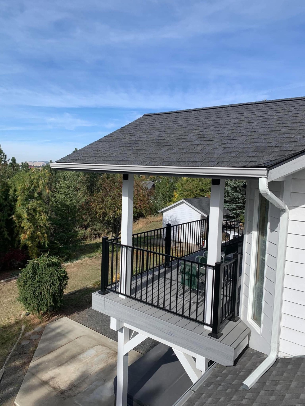 Finished shingle porch roof with white seamless gutter and downspout